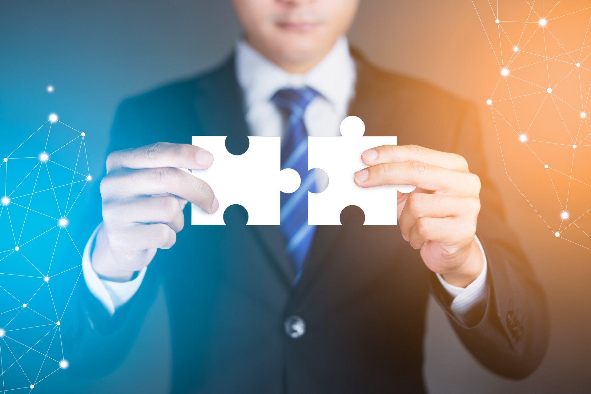 Businessman hands connecting puzzle pieces representing the merging of two companies or joint venture, partnership, Mergers and acquisition concept.